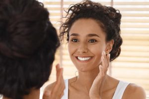 Mujer aplicando crema en la cara botón de oro